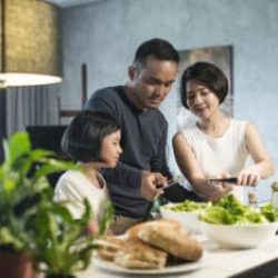 Happy Asian family preparing food in the kitchen.